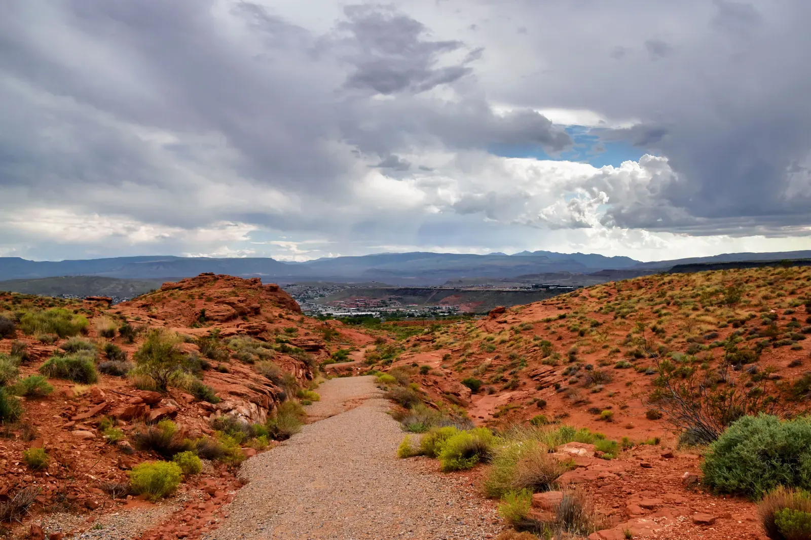 A desert trail through red rock and scrub near St. George, Utah, under a cloudy sky